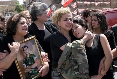 والدة احد الجنود القتلى تحمل صورته أثناء تشييع جثمانه