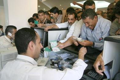 موظفون فلسطينيون فرحون أثناء استلامهم رواتبهم