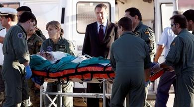 وأحد المصابين يحمل بالنقالة لدى وصولهم جميعاً إلى قاعدة توريجون الجوية قرب مدريد أمس