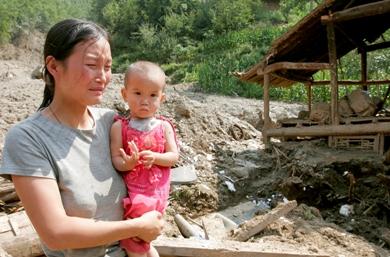 امرأة تبكي بعد أن دمر الفيضان منزلها بالكامل