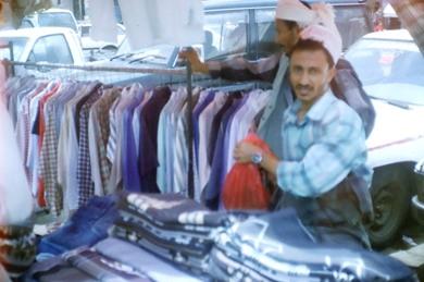 بائعون يستعرضون الملابس في سوق الحراج