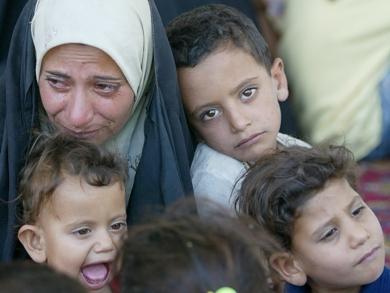 امرأة عراقية سنية مع اطفالها أثناء هروبها من مساكنها بسبب سوء الاوضاع الامنية
