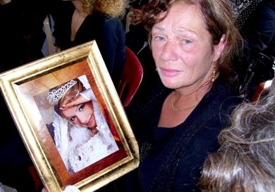 والدة الفتاة التي توفيت في وقت سابق تحمل صورة ابنتها وهي تبكي