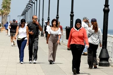 رجال ونساء لبنانيون يتجولون على شاطئ حي المنارة في بيروت أمس بعد توقف الاشتباكات