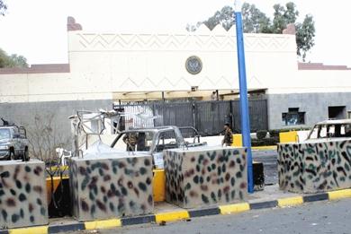 جندي يمني أمام السفارة الأميركية وآثار الاعتداء ظاهرة أمامه يوم أمس الأول