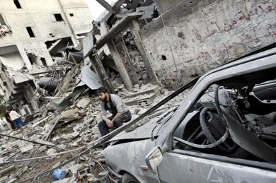 رجل غزاوي يجلس بين أطلال منزله وبجوار سيارة مدمرة بعد قصف إسرائيلي على القطاع أمس