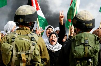 فلسطينيات يصرخن في وجوه جنود إسرائيليين في تظاهرة بقرية بيلين قرب رام الله أمس