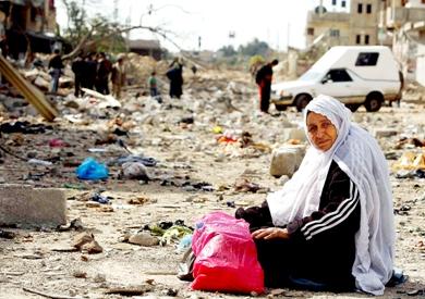 امرأة فلسطينية منكوبة تجلس بالقرب من منزلها الذي هدمته غارة جوية إسرائيلية في رفح شمال القطاع أمس
