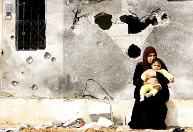 امرأة فلسطينية وابنتها أمام منزلهما المتأثر بقذائف إسرائيلية