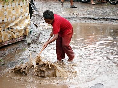 أحد الأطفال بحوطة لحج يقوم بتصريف مياه الأمطار أمام محله