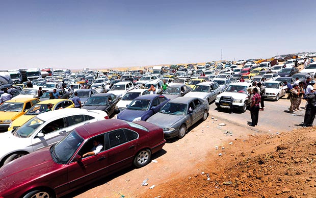 عراقيون هاربون من محافظة نينوى ينتظرون في سياراتهم عند نقطة تفتيش قبل الدخول للمناطق الكردية غرب أربيل أمس