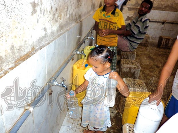 طفلة تقوم بتعبئة قنينة مياه للشرب