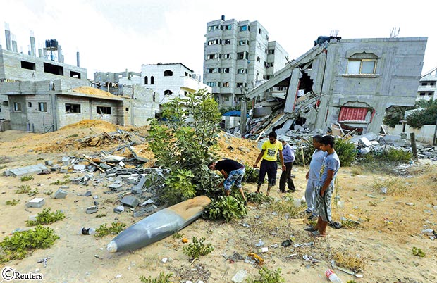 فلسطينيون ينظرون إلى قذيفة يقول شهود إنها أطلقت من طائرة عسكرية إسرائيلية