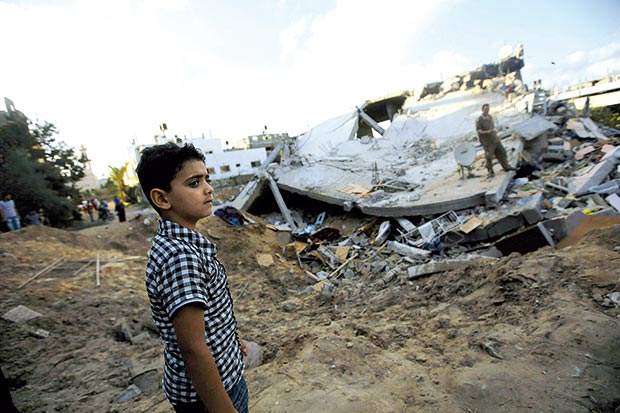صبي فلسطيني يقف بجانب منزل دمرته غارة جوية إسرائيلية على بيت لاهيا شمال غزة