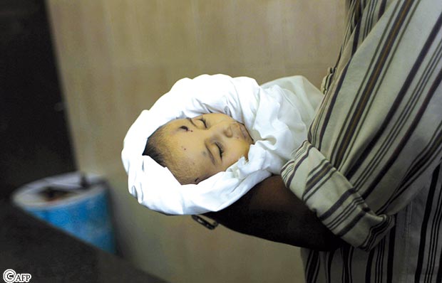 فلسطيني يحمل جثة الرضيع فارس المحموم في المشرحة أمس