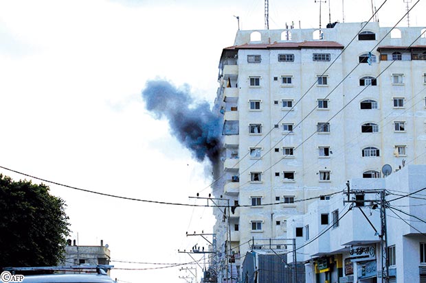 دخان يتصاعد بعد إصابة قذيفة إسرائيلية لمبنى سكني في رفح أمس