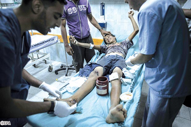أطباء في بيت لاهيا يعالجون صبيا فلسطينيا ) 9 سنوات( أصيب بها بعد غارة جوية إسرائيلية