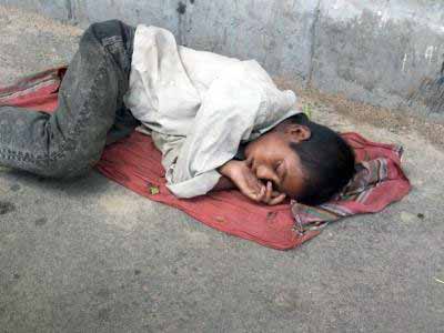 طفل نائم على الرصيف في الشارع