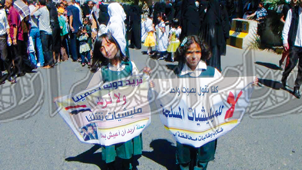 طالبتان تحملان شعارات مناهضة لوجود المليشيات المسلحة