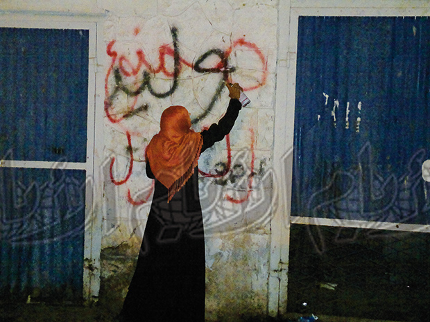 ناشطة تكتب تحذير على الجدار المقابل لخيمة النساء