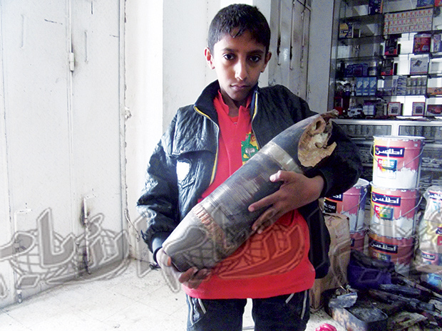 أحد أطفال الضالع يحمل بقايا من قذيفة دبابة سقطت على أحد منازل السكان