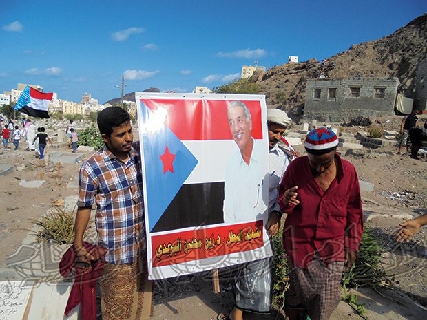 ناشطون جنوبيون يرفعون صورة للشهيد داخل مقبرة القطيع بعدن أمس