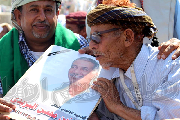 رجل مسن يقبل صورة الشهيد د.زين اليزيدي 