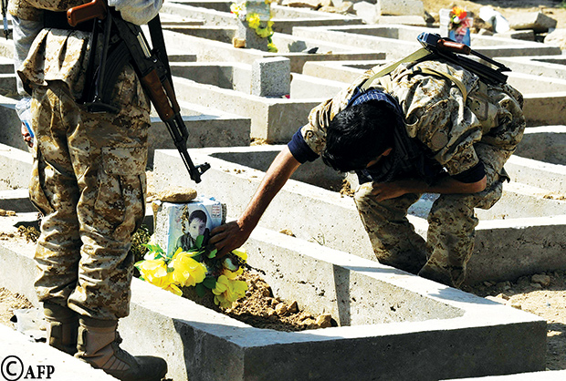 عناصر من أنصار الله يضعون الزهور على قبر أحد ضحايا تفجيرات صنعاء