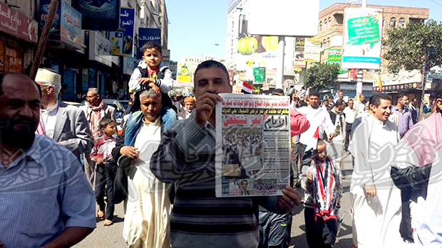 مواطن يرفع صحيفة «الأيام» (طبعة تعز) في المظاهرة أمس