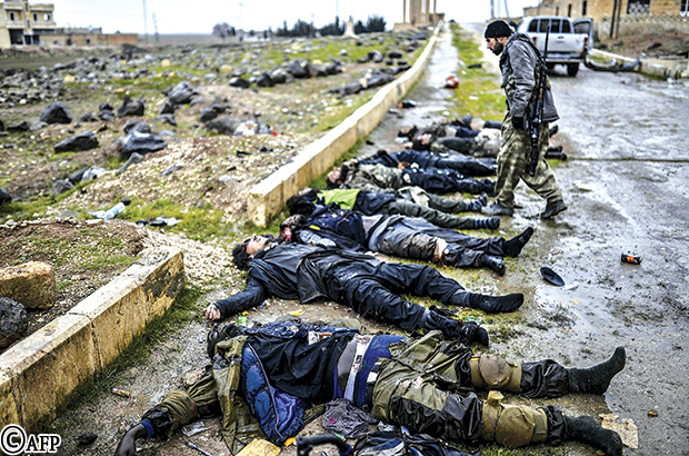 مقاتل كردي بنظر إلى جثث عناصر الدولة الإسلامية شرق مدينة كوباني أمس
