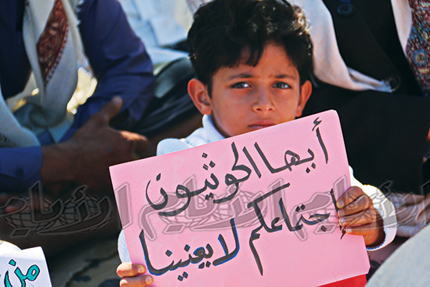 طفل يحمل لافتة في ساحة الحرية بتعز