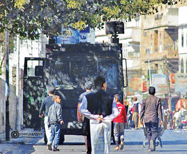 متظاهرون يقفون أمام عربة تابعة للحوثيين