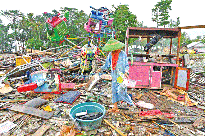 امرأة تنقذ الأشياء الثمينة من متنزه ترفيهي مؤقت ضربه إعصار تسونامي في قرية سمبر جايا في سومور - بانديغلانج 
