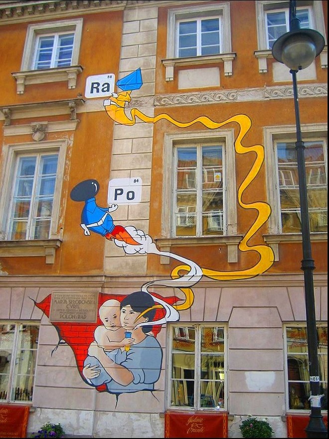 جدارية على المبنى الذي ولدت به ماري صور الطفلة ماريا سكوودوفسكا وهي تحمل أنبوب اختبار تخرج منه العناصر الكيميائية التي ستكتشفها عندما تكبر الراديوم Raوالبولونيوم Po