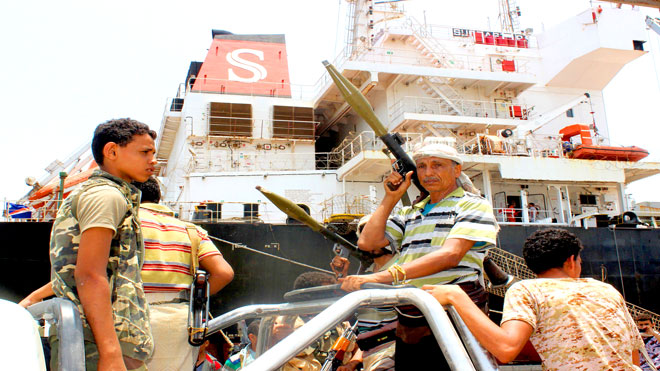 مقاتل متمرد من الحوثيين يحمل قاذفة  (RPG) يركب مع آخرين في ظهر شاحنة صغيرة أثناء الانسحاب من ميناء الصليف