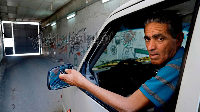 يستخدم الفلسطيني عمر حجاجلة جهاز التحكم عن بعد لفتح بوابة النفق التي تربط منزله في القدس بالولجة ، قريته في الضفة الغربية المحتلة
