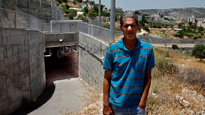 عمر حجاجلي يقف بجوار النفق الذي يربط منزله في القدس بالولجة ، قريته في الضفة الغربية المحتلة