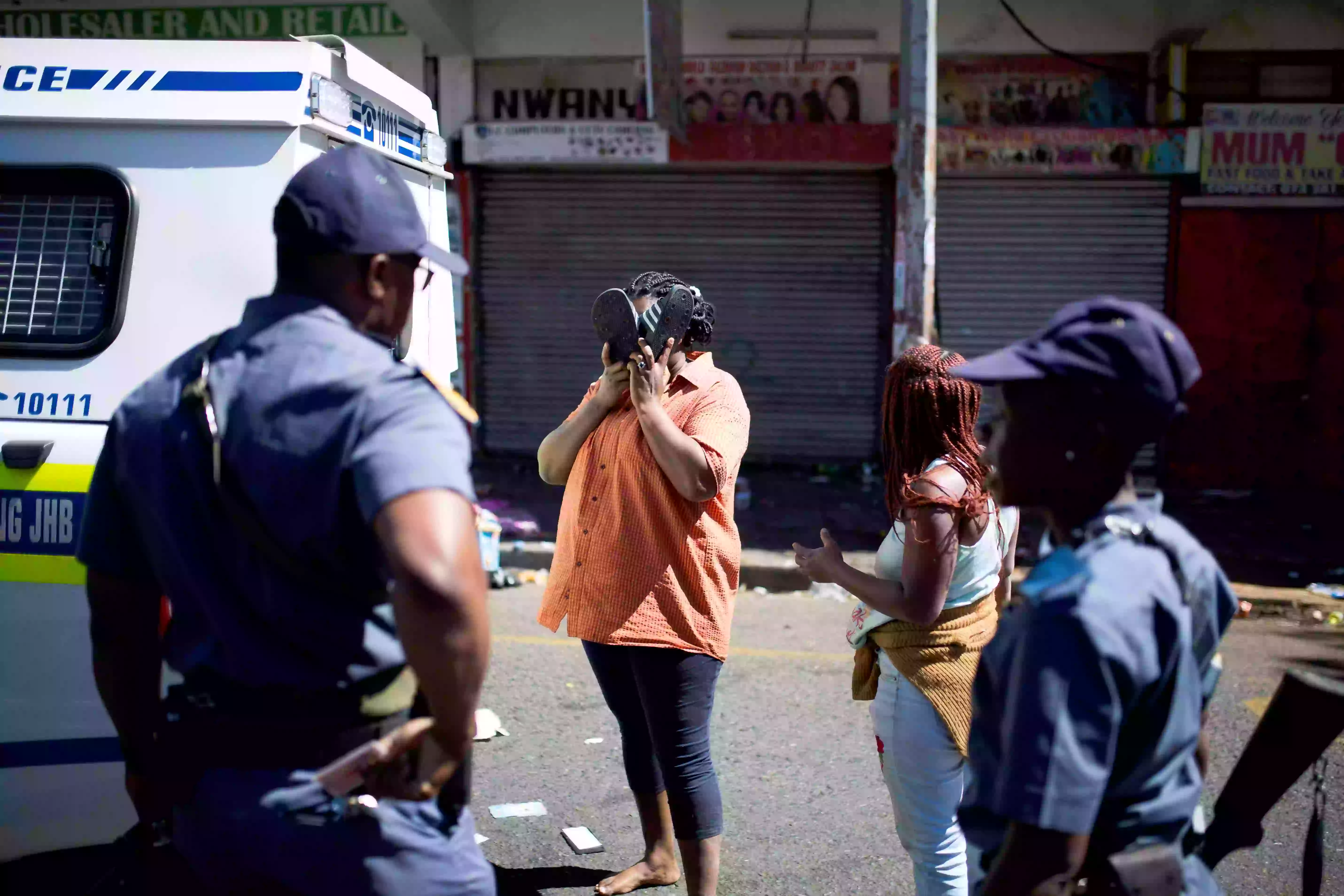 امرأة جنوب أفريقية تغطي وجهها أثناء احتجازها على أيدي ضباط الشرطة أثناء أعمال شغب في ضاحية تورفونتاين في جوهانسبرج