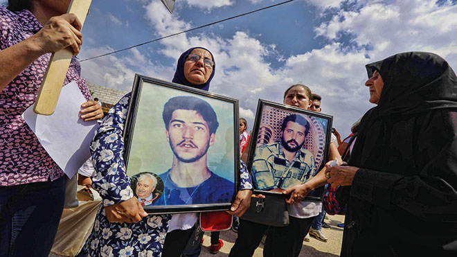 نسوة يحملن صورًا لأقاربهم الذين قتلوا خلال الاحتلال الإسرائيلي لجنوب لبنان ، أثناء مشاركتهن في مظاهرة أمام سجن الخيام