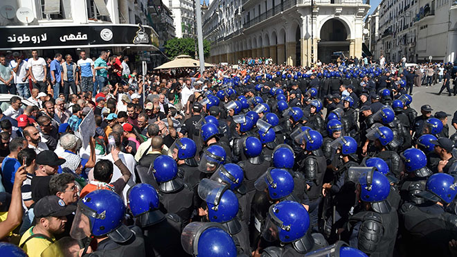 يواجه المتظاهرون الجزائريون رجال شرطة مكافحة الشغب خلال مظاهرة بالقرب من مبنى البرلمان في الجزائر