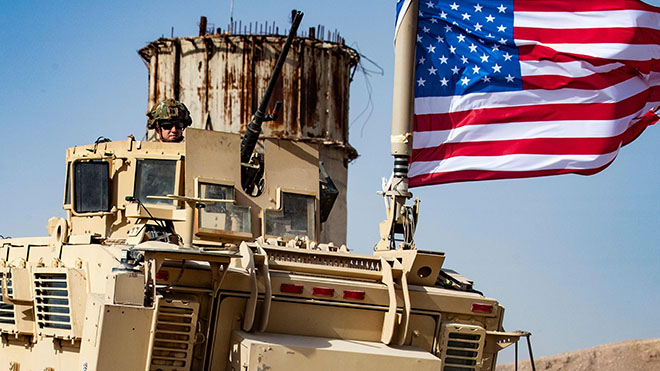 جندي أمريكي يجلس فوق مركبة مدرعة أثناء مظاهرة من الأكراد السوريين ضد التهديدات التركية بجانب قاعدة للتحالف الدولي