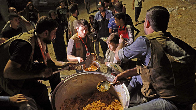 يوزع المتطوعون الطعام على السوريين الذين تم ترحيلهم مؤخراً لاجئين بسبب العملية العسكرية التركية في شمال شرق سوريا لدى وصولهم إلى مخيم بردرش