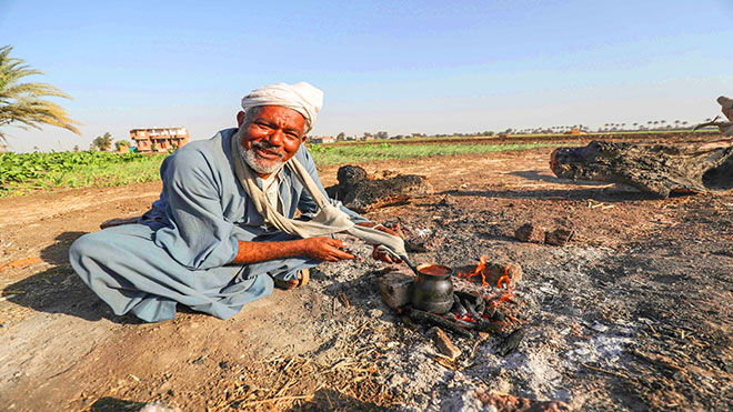 رجل مصري يعد القهوة على نار مفتوحة في حقل بقرية النحية ، أحد أفقر الأحياء في البلاد ، في محافظة أسيوط بوسط مصر