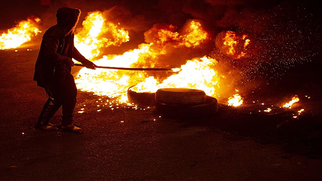 المتظاهرون العراقيون المناهضون للحكومة يقيمون حاجزًا محترقًا في مدينة البصرة الجنوبية أمس