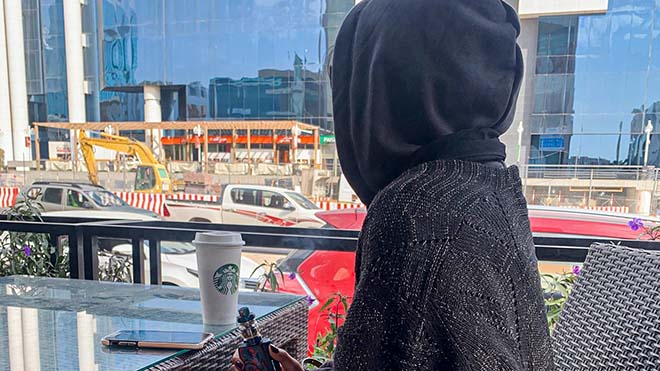 ريما ، امرأة سعودية تبلغ من العمر 27 عامًا ، تحمل سيجارتها الإلكترونية أثناء تهافتها في أحد المقاهي بوسط الرياض