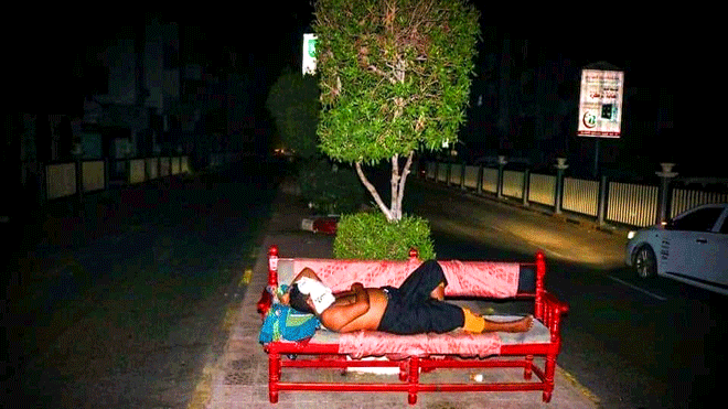 صورة نُشرت أمس لرجل ينام على الرصيف بينما تقبع المدينة بالظلام الدامس والحر الشديد بعدن