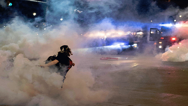 متظاهر يقذف عبوة غاز مسيل للدموع باتجاه شرطة ديترويت بعد اندلاع التوترات بسبب اعتقالات المتظاهرين في شوارع ديترويت بولاية ميشيغان