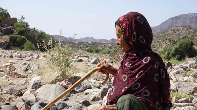 امرأة طاعنة في السن تنظر بعين الحسرة لأراضيها التي جرفتها السيول