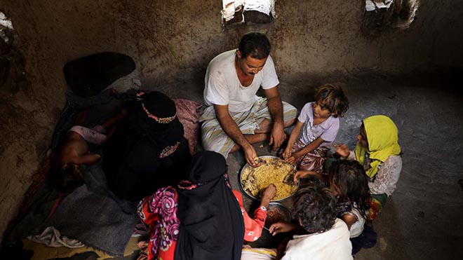 علي العمادي ، الذي يعمل حطابًا ، يتناول الغداء مع أسرته في منزلهم بقرية بمديرية خميس بنيساد بمحافظة المحويت - رويترز. 