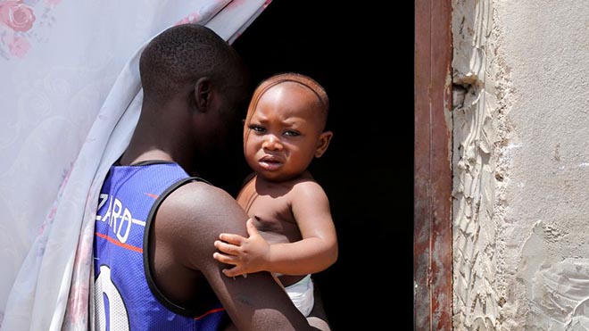 موسى مهاجر نيجيري يحمل ولده في "البيت الامن"